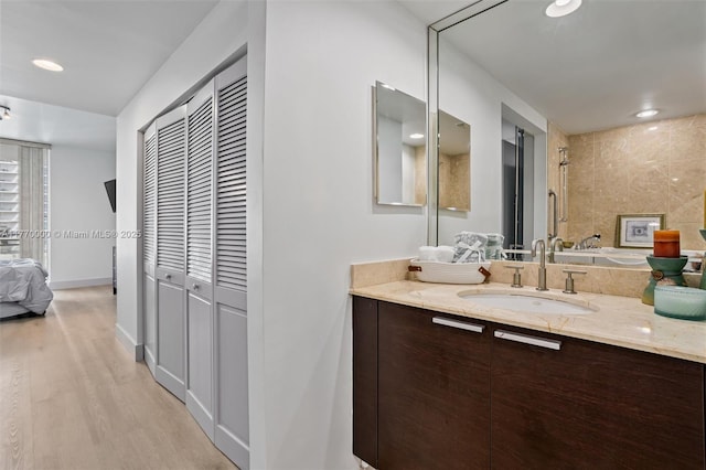 full bath featuring vanity, recessed lighting, baseboards, connected bathroom, and wood finished floors