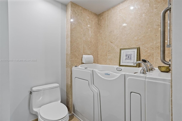bathroom featuring toilet and tile walls