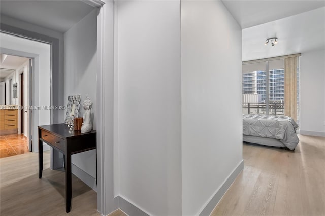 corridor featuring baseboards and light wood-style floors