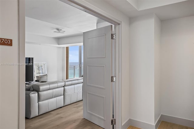 hall with baseboards and light wood-type flooring