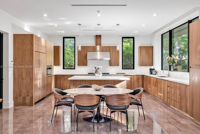 3232 Emathla St, Miami, FL 33133 - kitchen with modern cabinets, brown cabinets, a kitchen island, and under cabinet range hood
