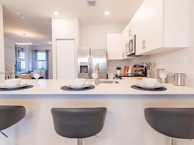 kitchen with light countertops, a peninsula, appliances with stainless steel finishes, and visible vents