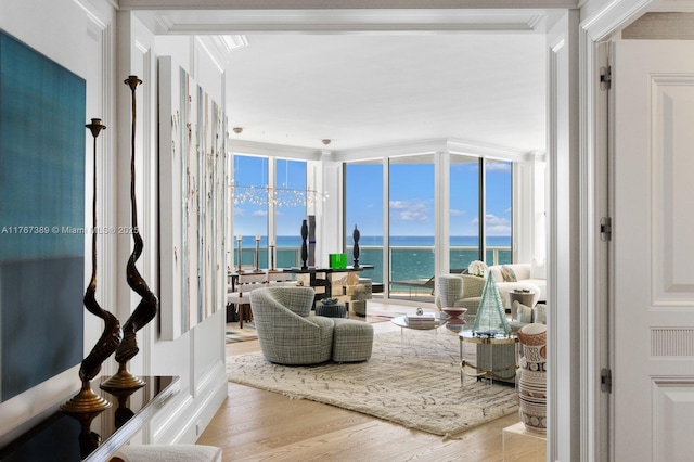 living room featuring crown molding, a water view, floor to ceiling windows, and wood finished floors