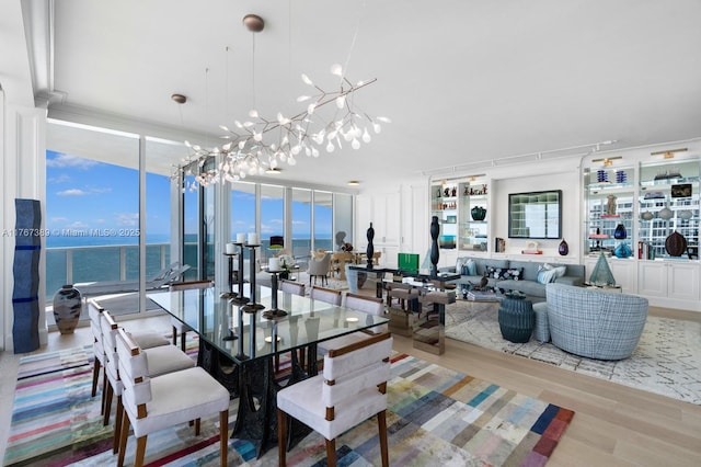 dining area featuring wood finished floors, a notable chandelier, and a wall of windows
