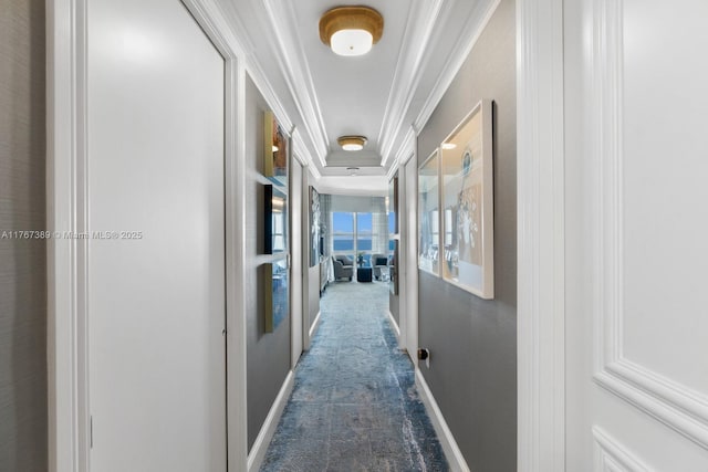 hallway with crown molding, carpet, and baseboards