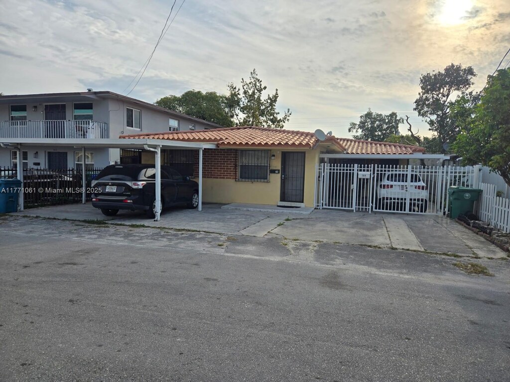 791 NW 22nd Pl, Miami, FL 33125 - view of front of property featuring stucco siding, fence, a tiled roof, and a carport