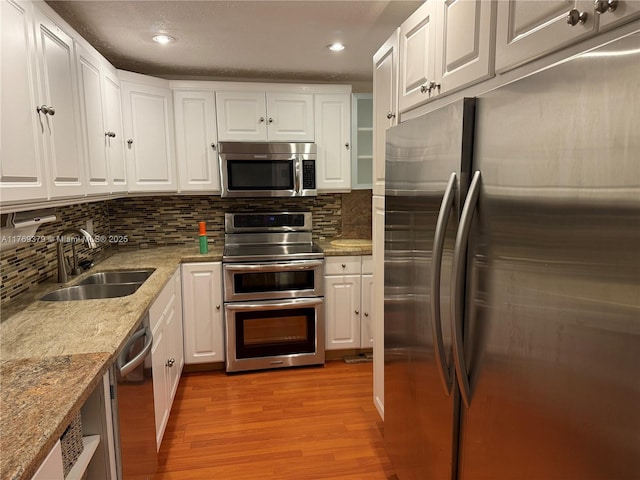 kitchen featuring white cabinets, light wood-style flooring, a sink, and stainless steel appliances