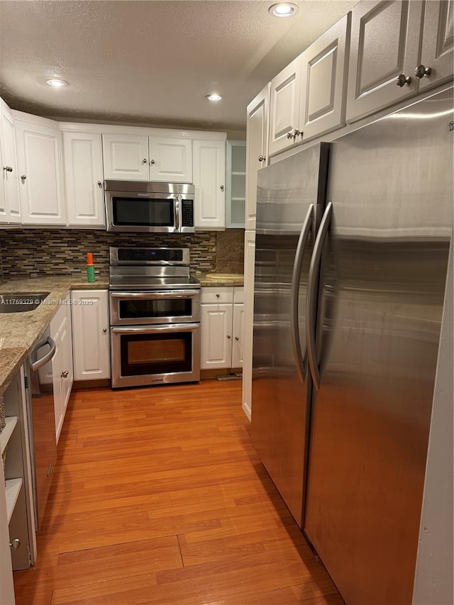 kitchen with white cabinets, light wood-style flooring, a sink, and stainless steel appliances
