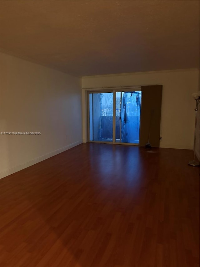 spare room with dark wood-style floors and baseboards