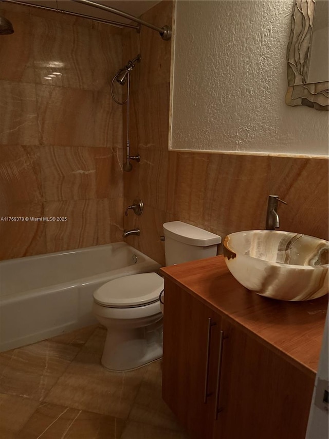 full bathroom featuring toilet, vanity, a textured wall, and shower / washtub combination