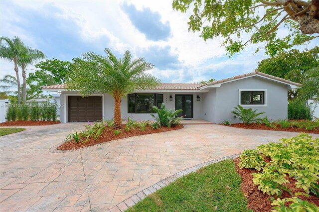 single story home with stucco siding, an attached garage, a tiled roof, and decorative driveway