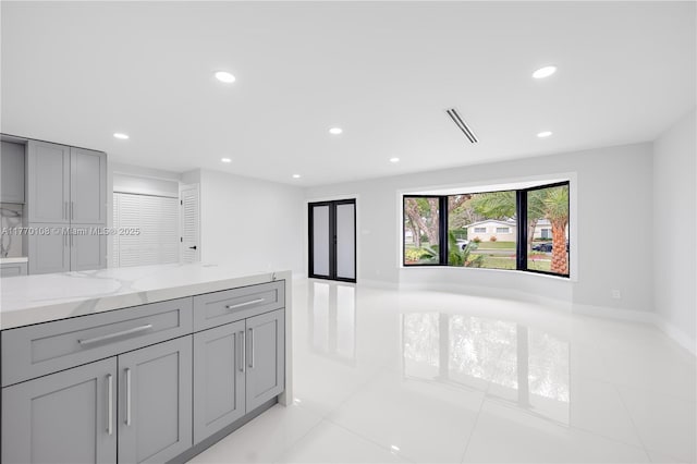 kitchen with recessed lighting, light tile patterned floors, gray cabinetry, visible vents, and light stone countertops
