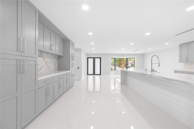 kitchen featuring recessed lighting, tasteful backsplash, gray cabinetry, and light stone counters