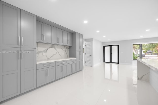 kitchen featuring gray cabinetry, decorative backsplash, light stone countertops, and recessed lighting