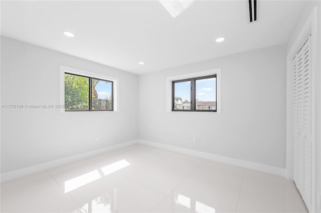 empty room with light tile patterned floors, visible vents, baseboards, and recessed lighting