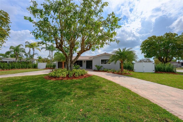 ranch-style house featuring concrete driveway, stucco siding, fence, a front yard, and a gate