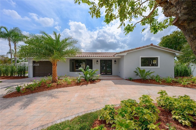 view of front of property with stucco siding, an attached garage, a tiled roof, and driveway