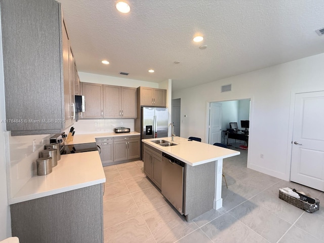 kitchen featuring light countertops, visible vents, a kitchen island with sink, stainless steel appliances, and a sink
