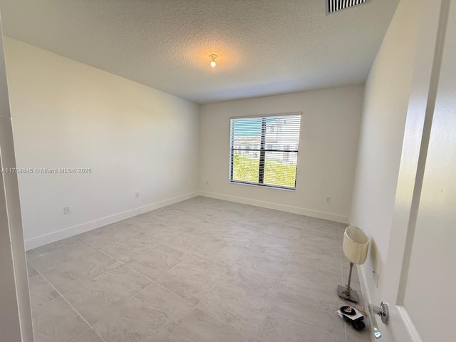 unfurnished room featuring baseboards, a textured ceiling, and visible vents
