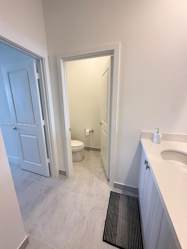 bathroom with toilet, vanity, and baseboards