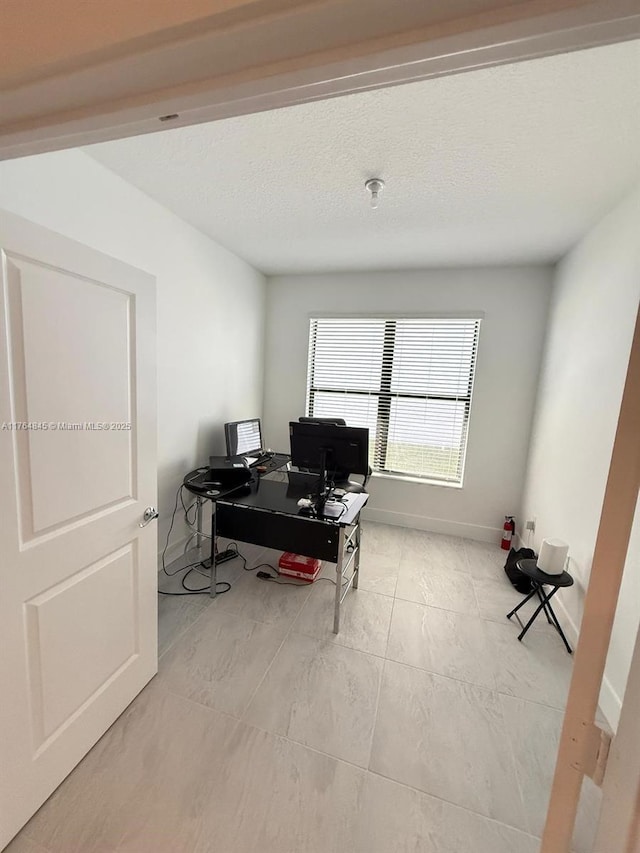 office area featuring baseboards and a textured ceiling