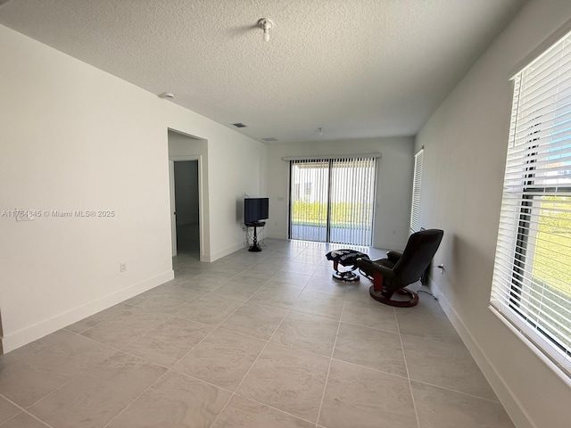 living area featuring light tile patterned flooring, baseboards, and a textured ceiling