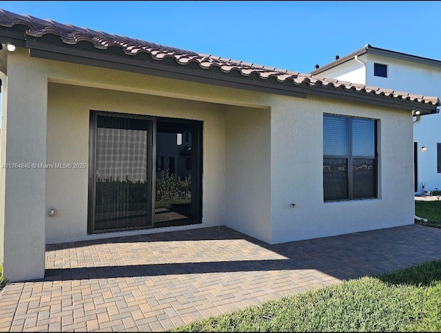 doorway to property featuring stucco siding and a patio area