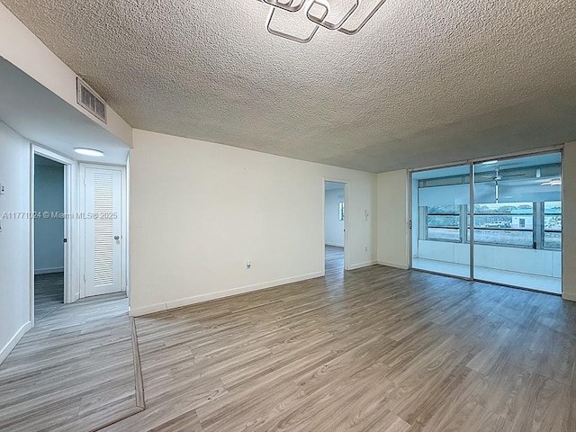 unfurnished room featuring baseboards, visible vents, and wood finished floors
