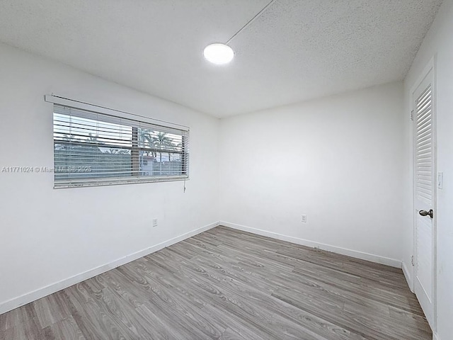 unfurnished bedroom featuring baseboards, a textured ceiling, and wood finished floors