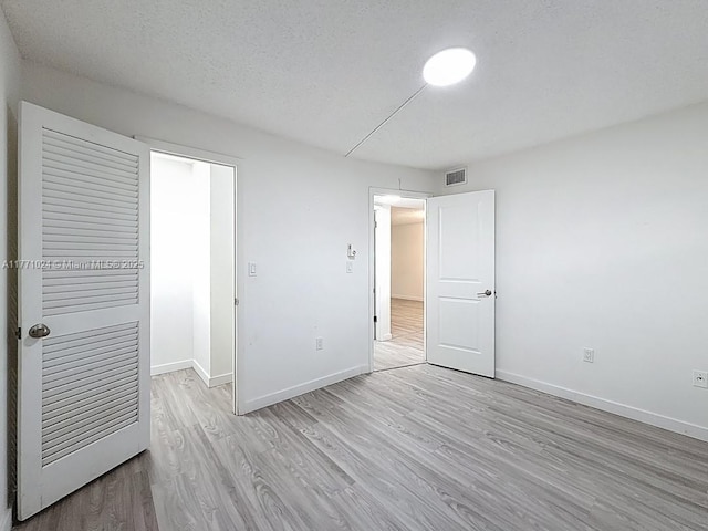 unfurnished bedroom featuring baseboards, light wood-style floors, and visible vents
