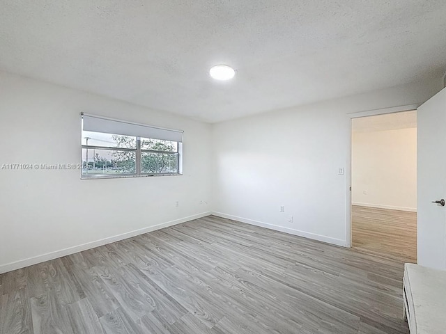 unfurnished room with baseboards, a textured ceiling, and wood finished floors