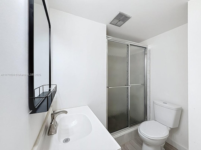 bathroom featuring a shower stall, visible vents, toilet, and a sink