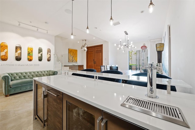 kitchen featuring light countertops, hanging light fixtures, open floor plan, track lighting, and an inviting chandelier