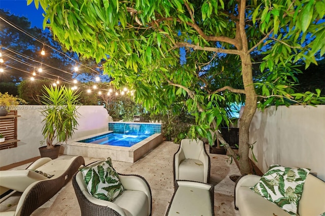 pool at night featuring a fenced backyard, an outdoor living space, a hot tub, and a patio area