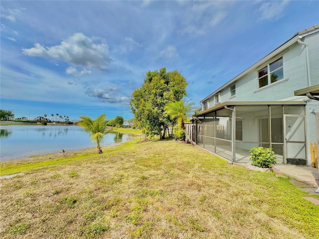 view of yard featuring a sunroom and a water view