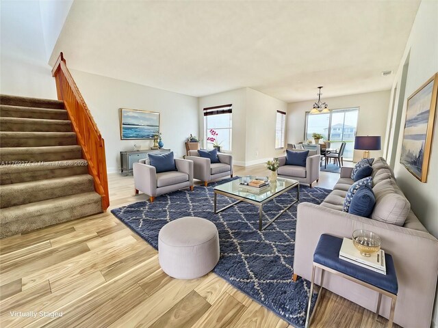 living area featuring visible vents, a chandelier, wood finished floors, and stairway