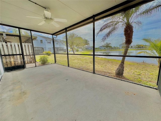 unfurnished sunroom with a ceiling fan and a water view