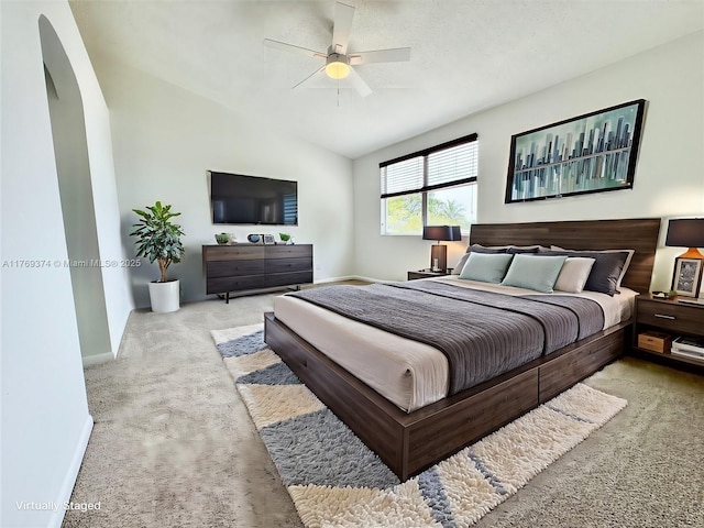 carpeted bedroom featuring baseboards, arched walkways, a ceiling fan, and vaulted ceiling