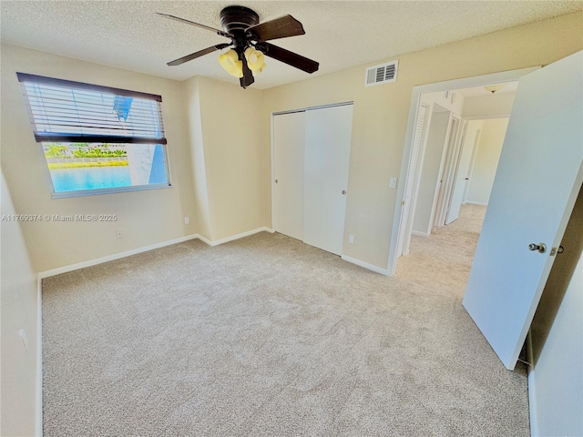unfurnished bedroom with ceiling fan, visible vents, baseboards, a closet, and carpet