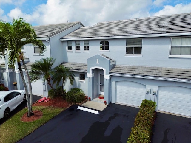 view of front of home with a tiled roof, an attached garage, driveway, and stucco siding