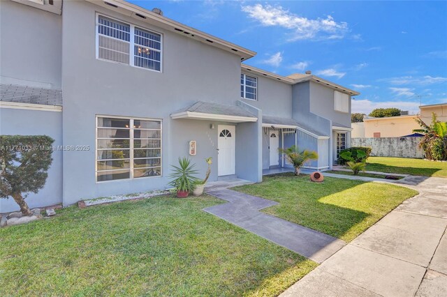 traditional-style home with a front lawn, stucco siding, and fence