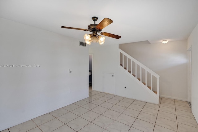 empty room with baseboards, visible vents, ceiling fan, and stairway