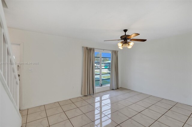 empty room with ceiling fan and light tile patterned floors