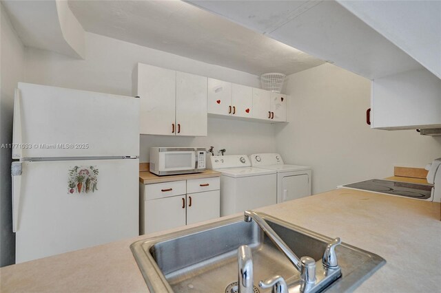 clothes washing area featuring a sink, laundry area, and washer and clothes dryer