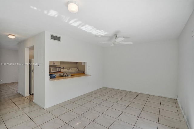 unfurnished room with washer and clothes dryer, visible vents, and ceiling fan
