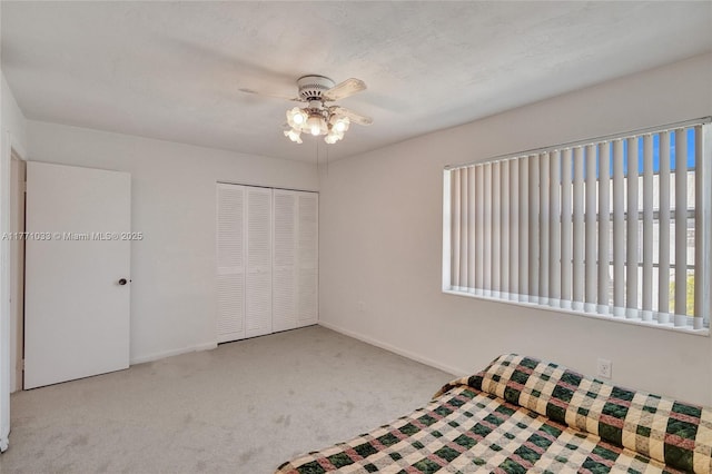 unfurnished bedroom featuring a closet, carpet flooring, ceiling fan, and baseboards