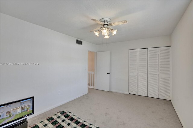 unfurnished bedroom with baseboards, carpet floors, visible vents, a ceiling fan, and a closet