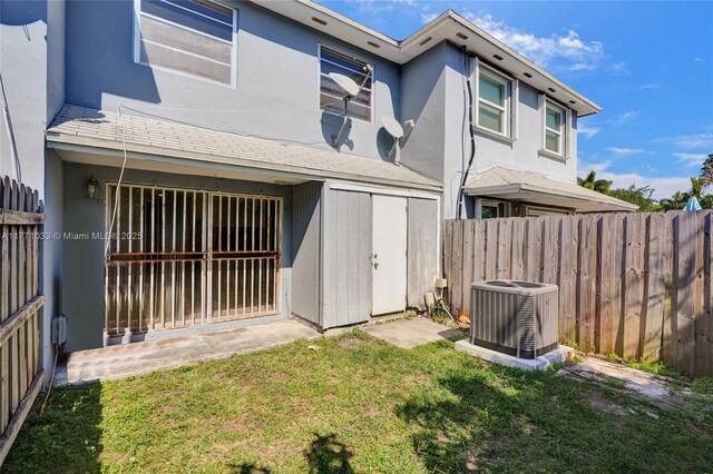 rear view of property featuring central air condition unit, a lawn, stucco siding, and fence private yard