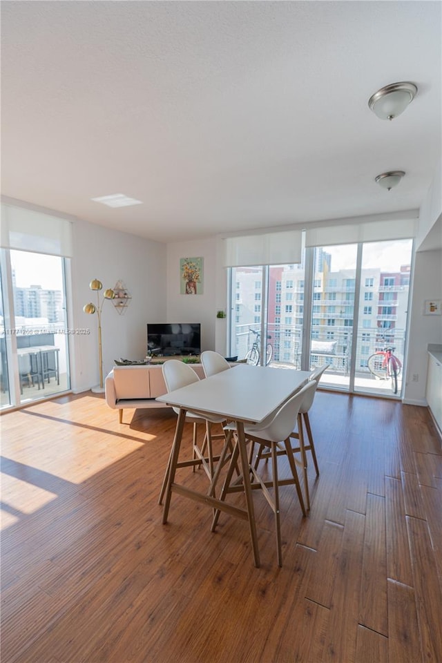 dining space with wood finished floors and a wall of windows