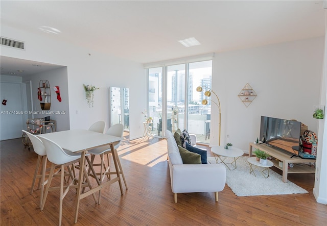 dining room with expansive windows, visible vents, and wood finished floors